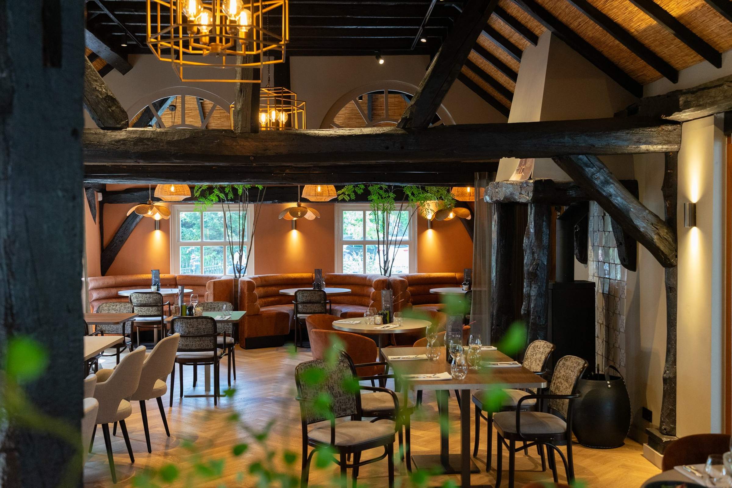 De zaal van Brasserie Bij Floor in Oisterwijk, met houten balken en warme hanglampen boven de tafels
