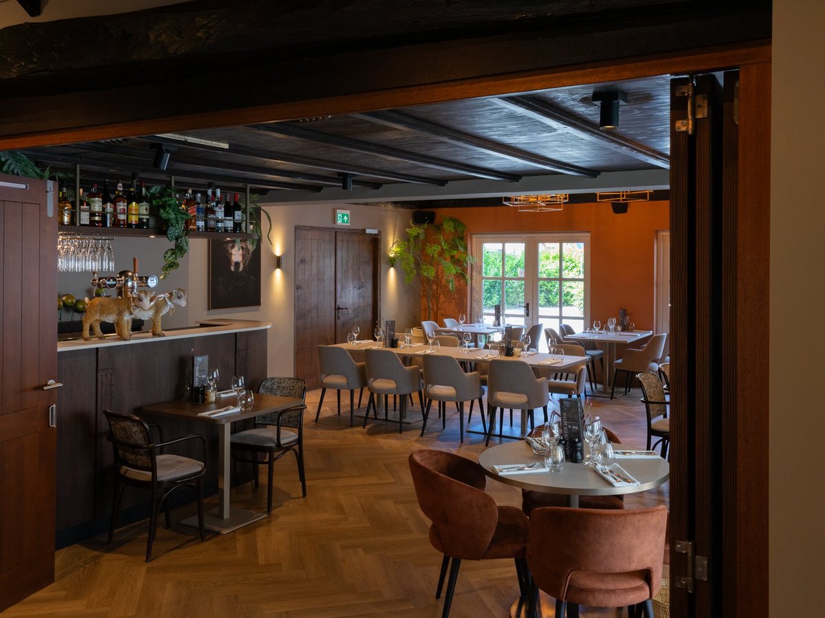 De bar en de zaal van Bij Floor bij daglicht, met tafels op een visgraatvloer