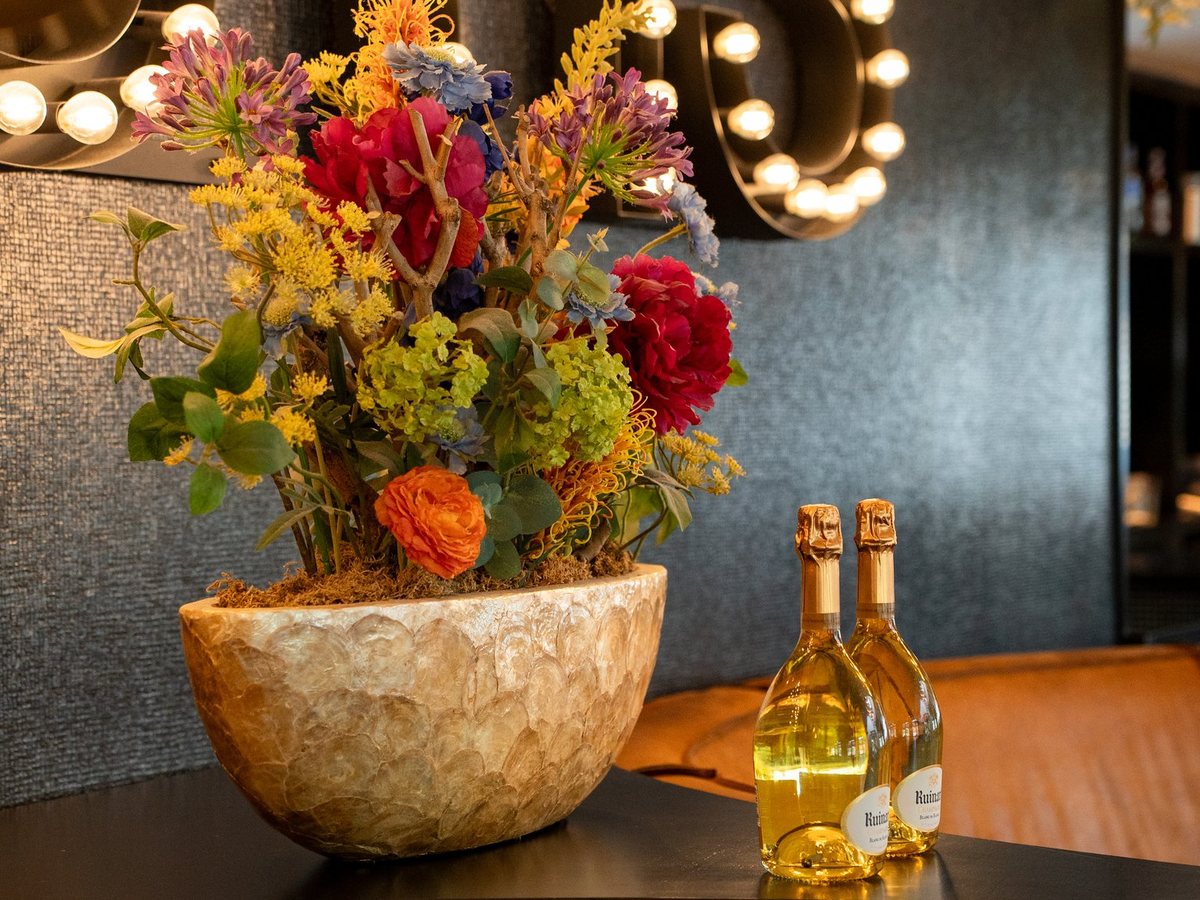 Een bos bloemen in een vaas op de bar, met lampjes op de achtergrond